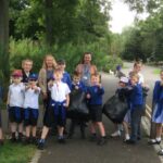 a large group of pupils and teachers on an outdoors litter pick