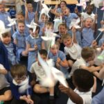 large group of pupils all holding up small windmills