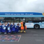 a group of pupils standing in front of a new electric bus