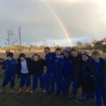 pupils outside in a group with arms linked standing in front of a rainbow