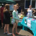 pupils outside on a sunny day standing in front of stalls selling products