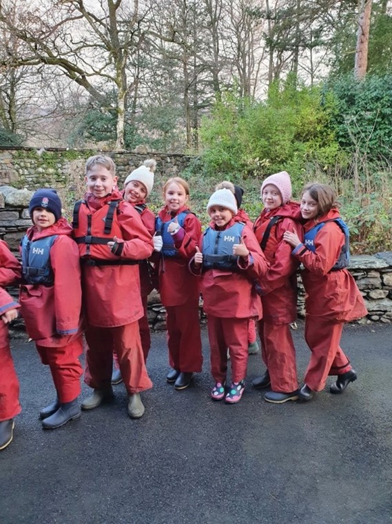pupils on an external trip wearing waterproofs standing in a row 